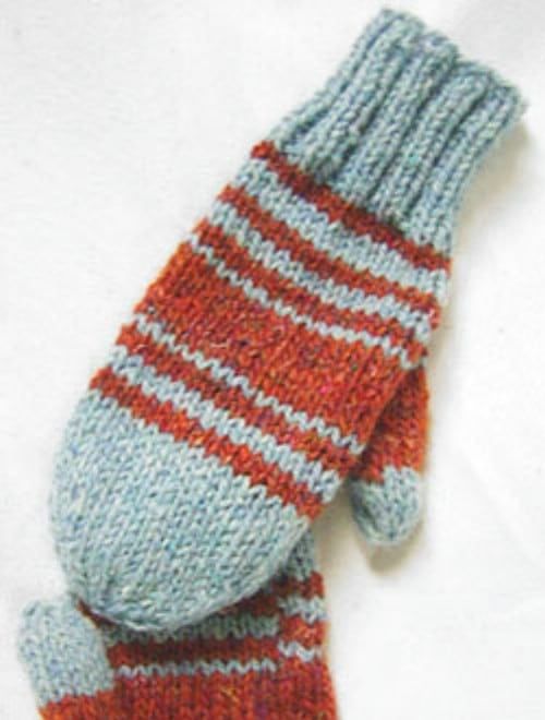 a knitted mitten laying on top of a white sheet with red and blue stripes