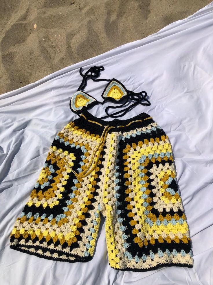 a crocheted yellow and black shorts laying on top of a white bed sheet