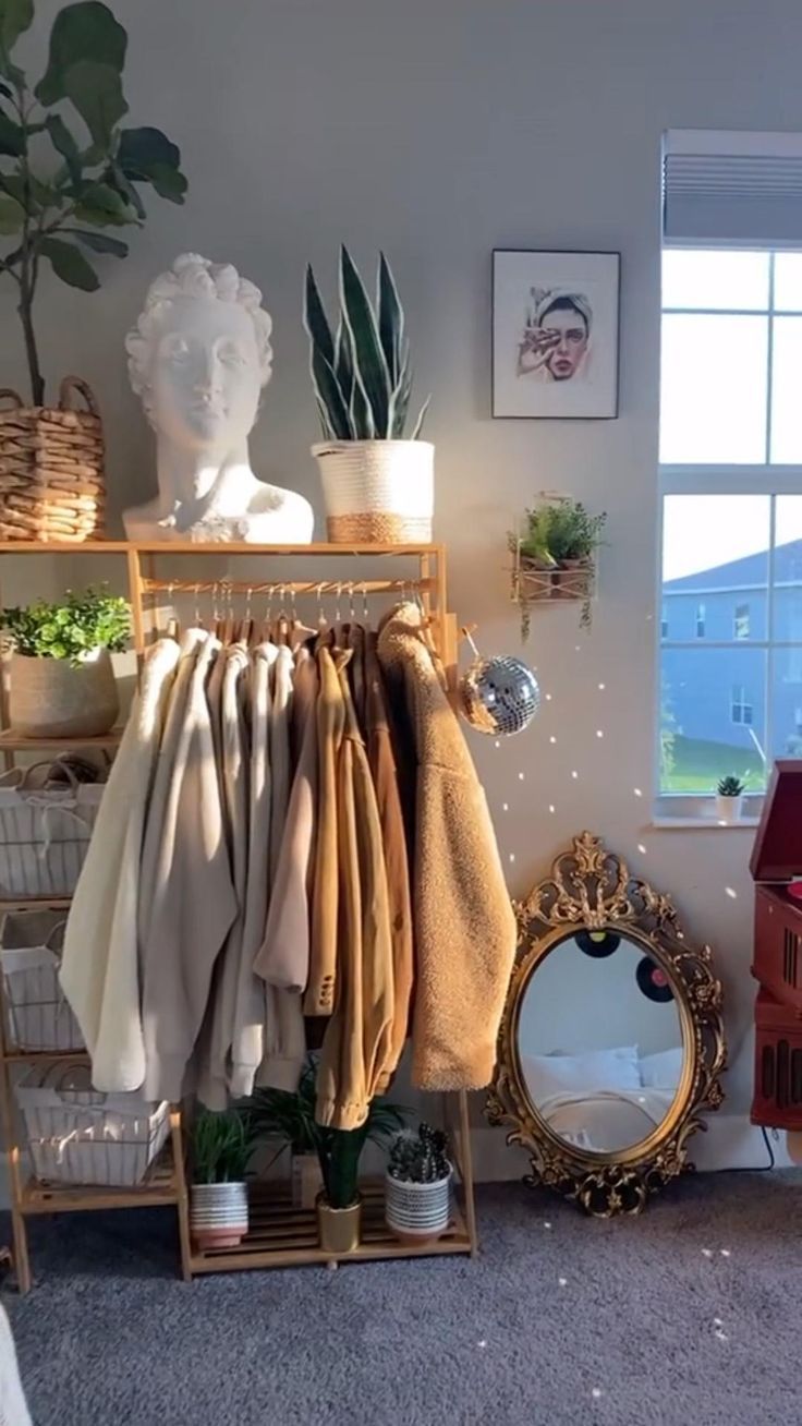 a room with clothes hanging on racks and a mirror in front of the window next to it