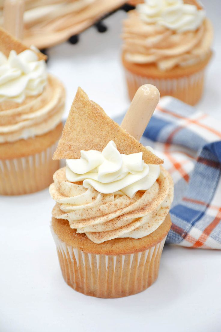 some cupcakes with white frosting and a wooden stick sticking out of them