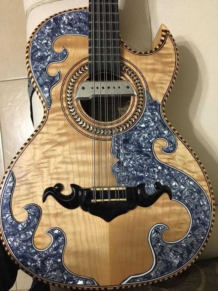 a wooden guitar with blue and gold designs on it's back, sitting in front of a white wall