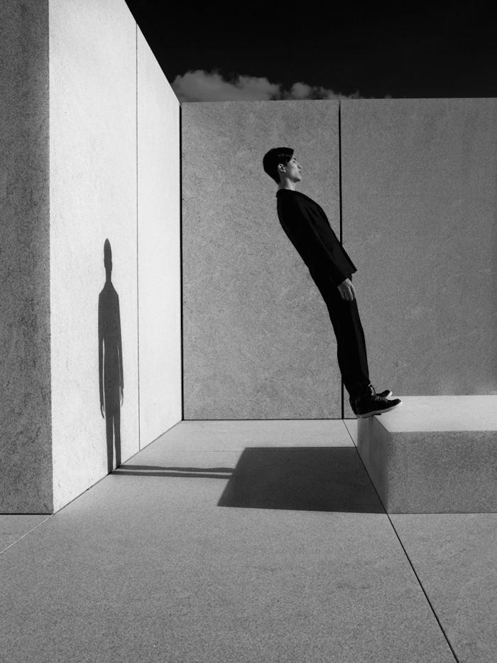 an image of a man standing in the middle of a room with his shadow on the wall