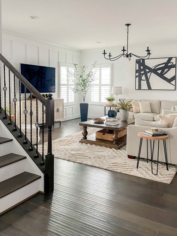 a living room filled with furniture and a stair case next to a white couch on top of a hard wood floor