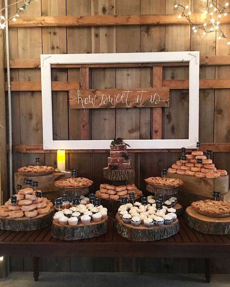 a table topped with lots of donuts next to a wooden sign that says how sweet it is