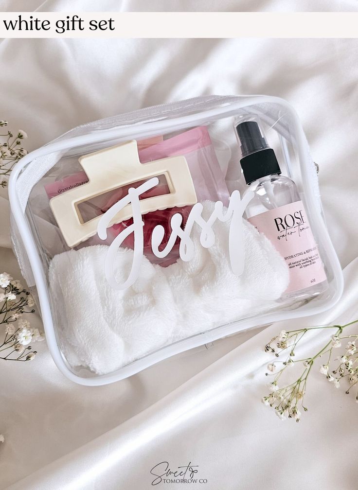 a white gift set in a clear case with flowers and soaps on the side