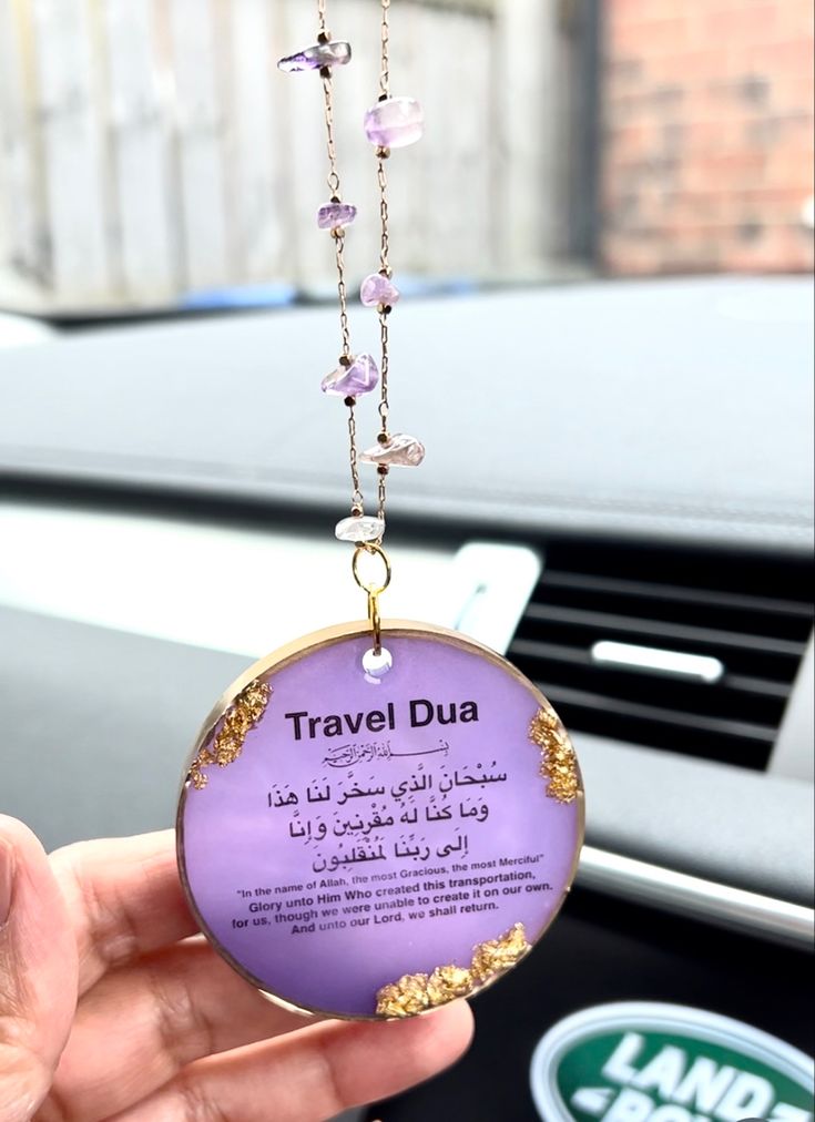 a person is holding up a travel dua in their hand and it's attached to the dashboard of a car