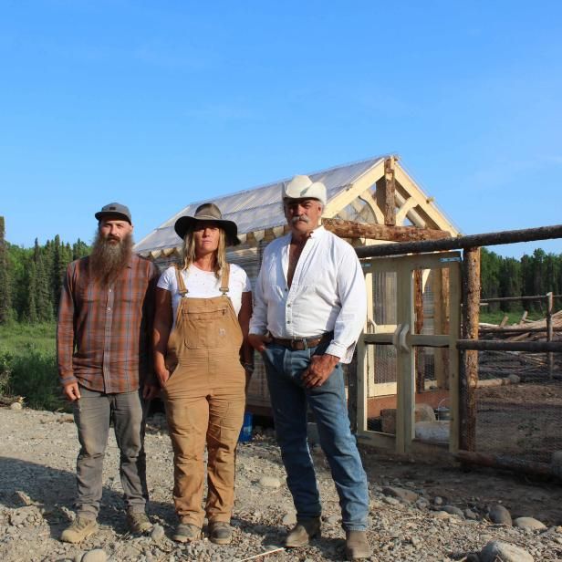 three people standing next to each other in front of a building that is being built