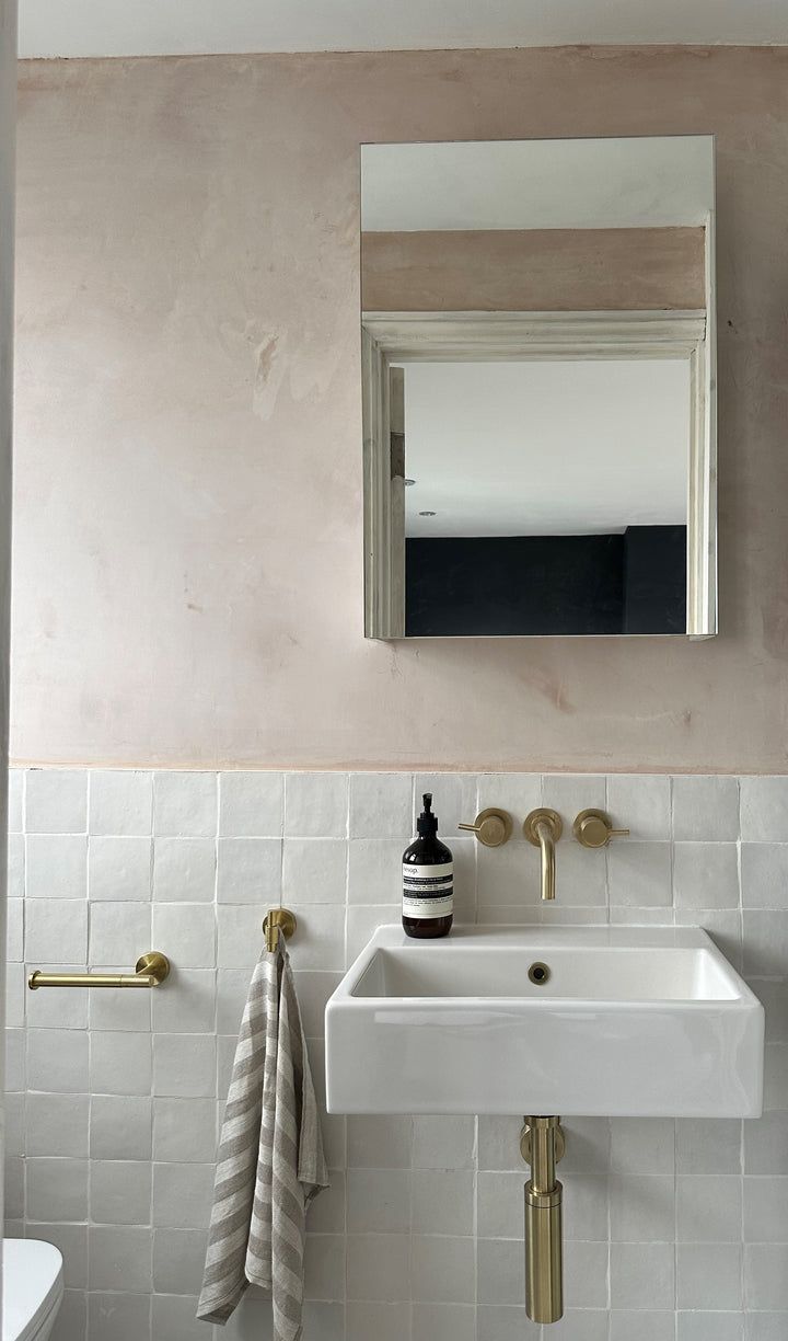 a white sink sitting under a bathroom mirror next to a wall mounted faucet