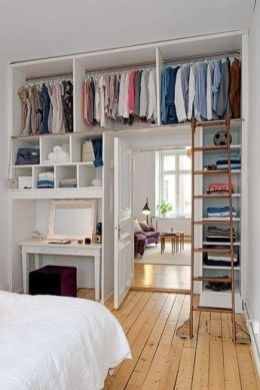 a bedroom with a bed, desk and shelves filled with clothes on top of them