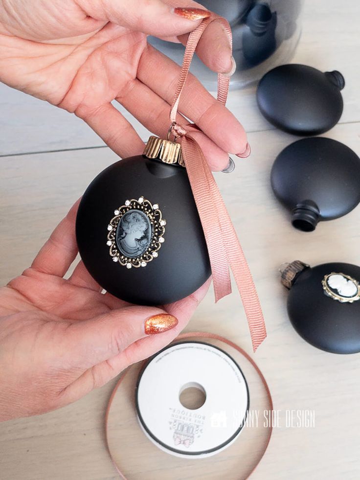 a person holding an ornament in their hand next to some other ornaments on a table