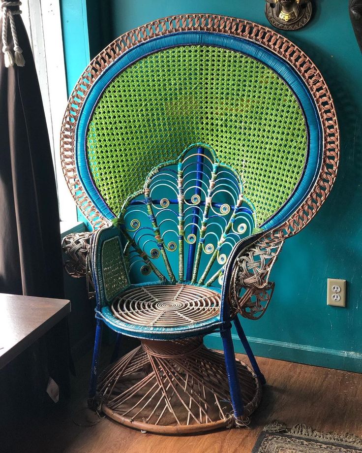 a peacock chair sitting in front of a window next to a blue wall and wooden floor