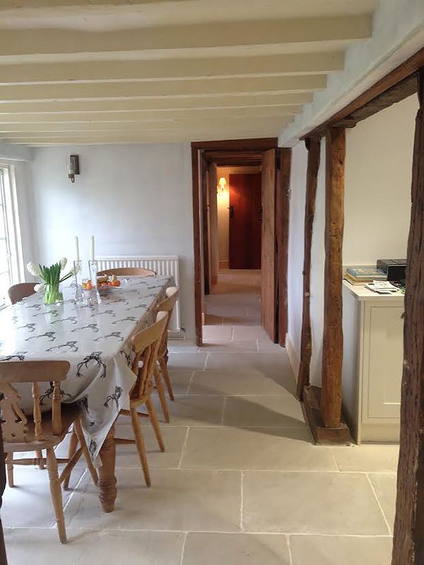 a dining room table and chairs in front of an open door with wooden beams on the ceiling