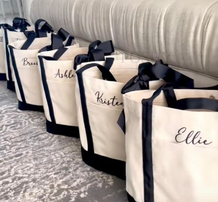 several bags with black bows are lined up on the floor next to a couch and wall