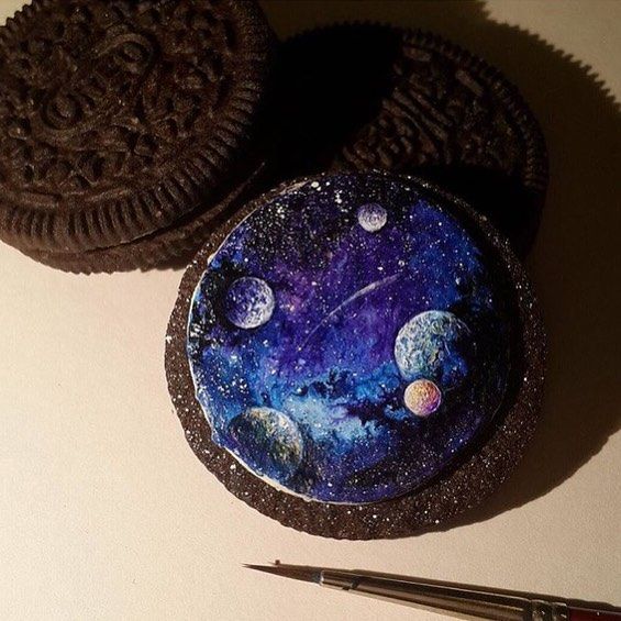 an oreo cookie sitting on top of a table next to some paint and scissors