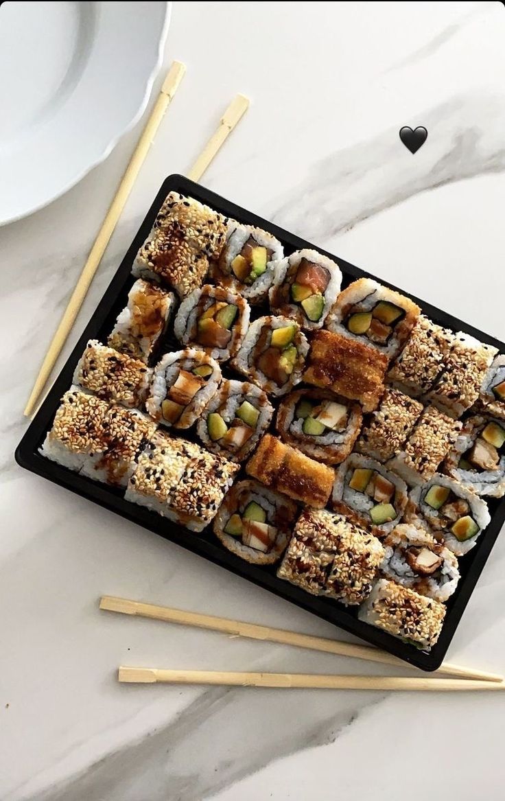 sushi on a tray with chopsticks next to it