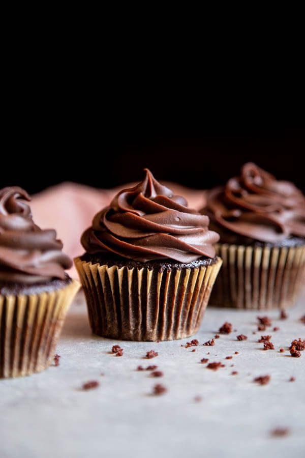 three cupcakes with chocolate frosting and sprinkles on a table