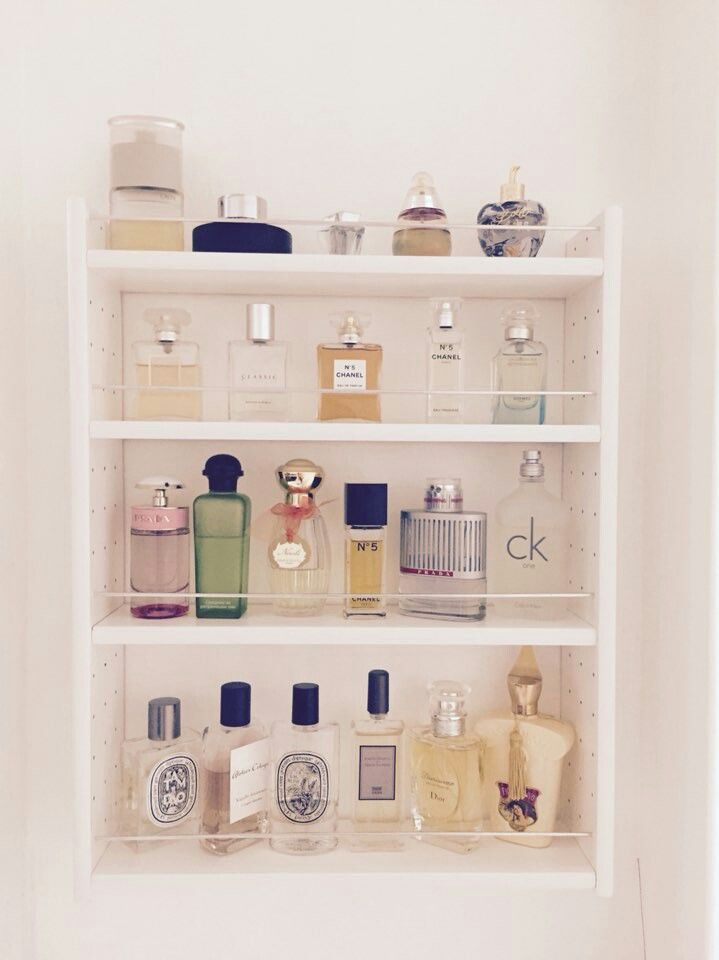 a white shelf filled with lots of different types of perfumes