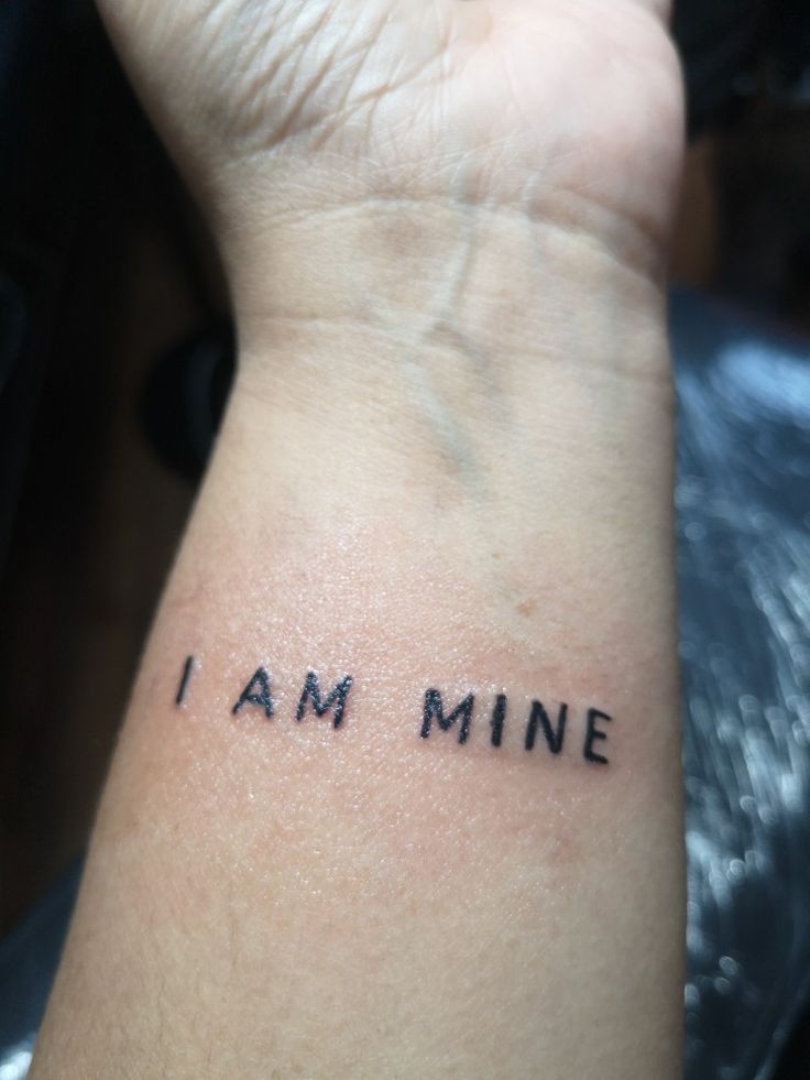 a person's wrist with the words i am mine written on it, in black ink