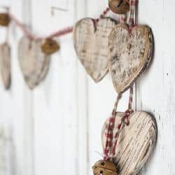 three wooden hearts hanging from a string on a white wall with red checkered twine