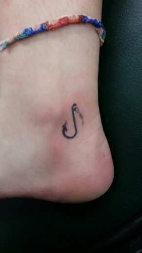 a small anchor tattoo on the side of a person's foot, with an arrow in it