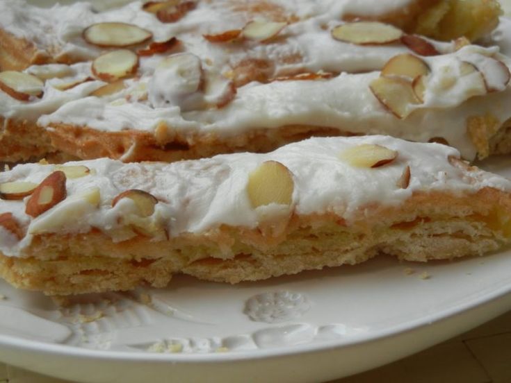 two pieces of cake sitting on top of a white plate with almonds and icing