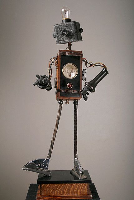 a robot made out of metal and wood with a clock on it's back