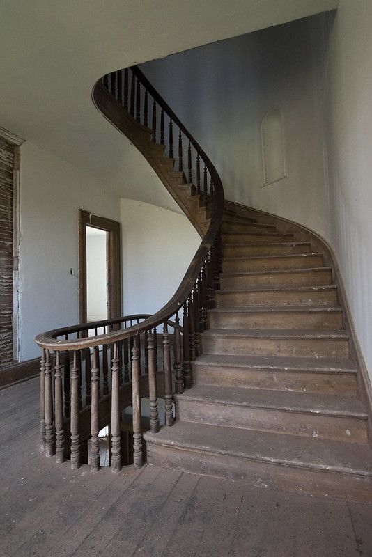 an empty room with a spiral staircase and wooden floors