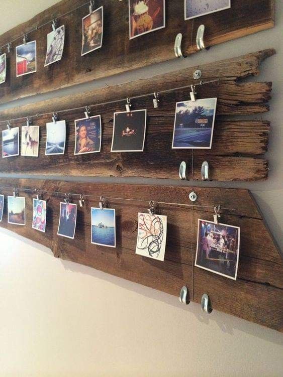 a wooden wall hanging with pictures and magnets attached to the pegs on it