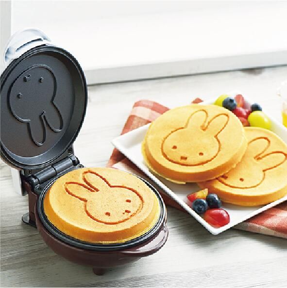 a waffle iron sitting on top of a table next to some cookies and fruit