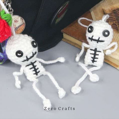 two crocheted skeleton keychains are sitting next to each other on a table