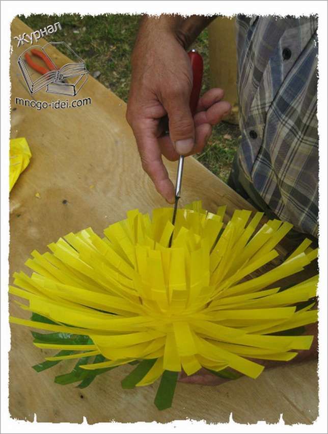 a person cutting paper flowers with a pair of scissors