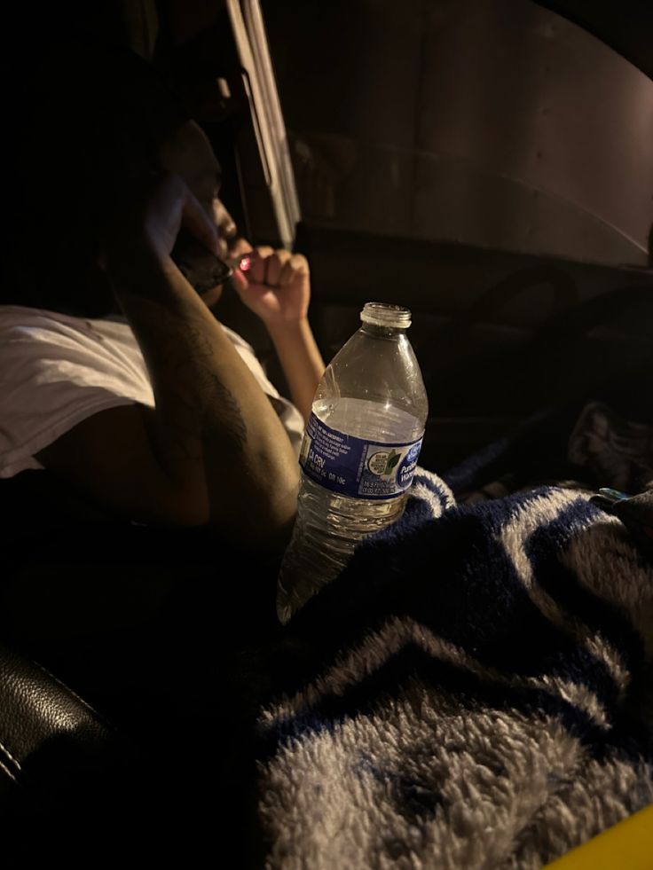 a bottle of water sitting on top of a bed next to a person laying down