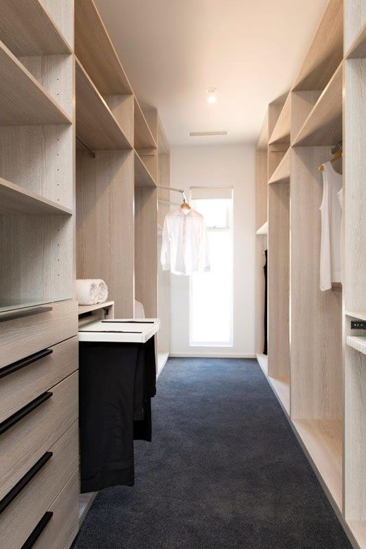 an empty walk in closet with clothes hanging on wooden shelves and black carpeted floor