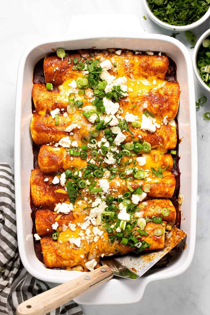 a casserole dish filled with chicken, cheese and green onion garnish