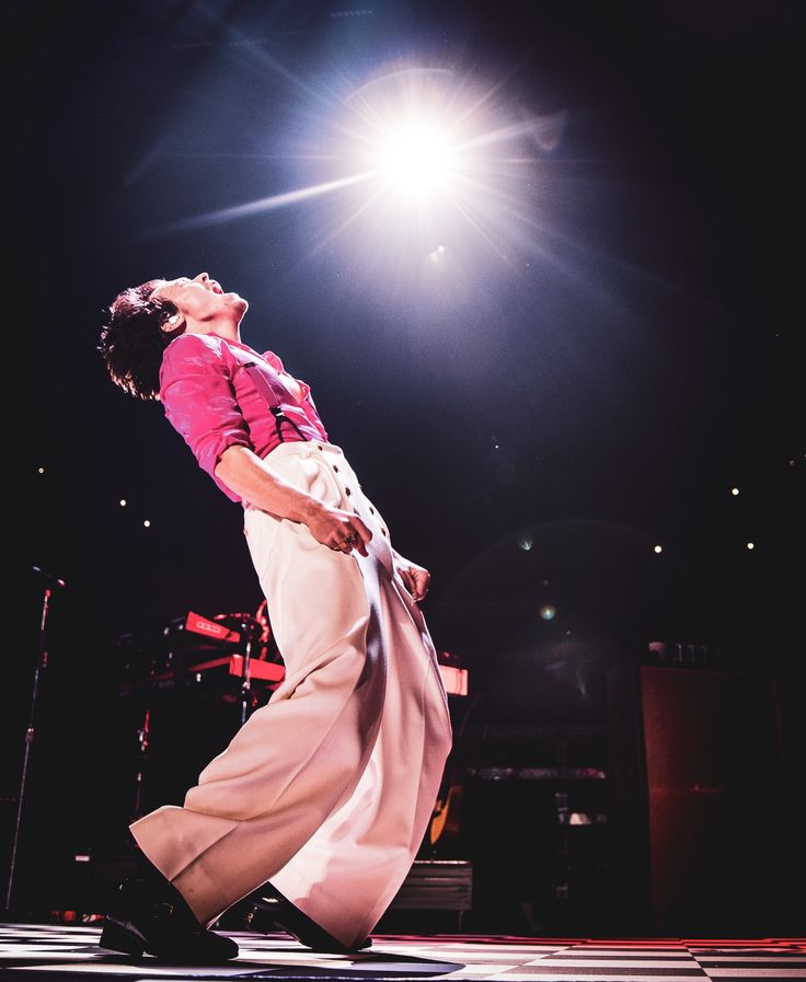 a woman standing on top of a stage in front of a microphone and some lights