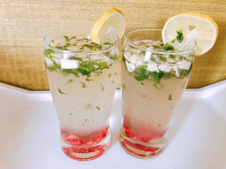 two glasses filled with drinks sitting on top of a table