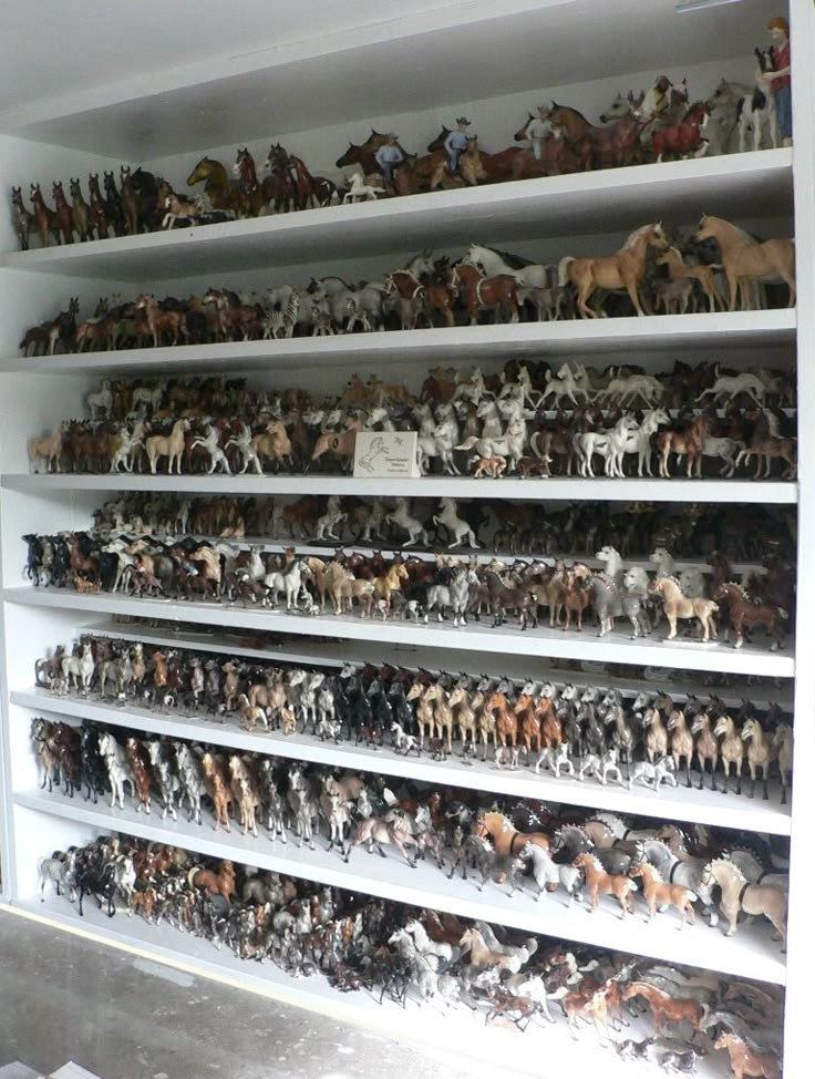 many toy horses are on shelves in a room