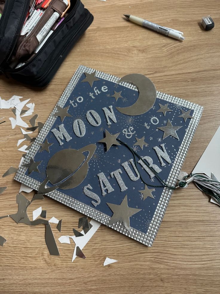 a card with the words moon and saturn on it, surrounded by cut out paper stars