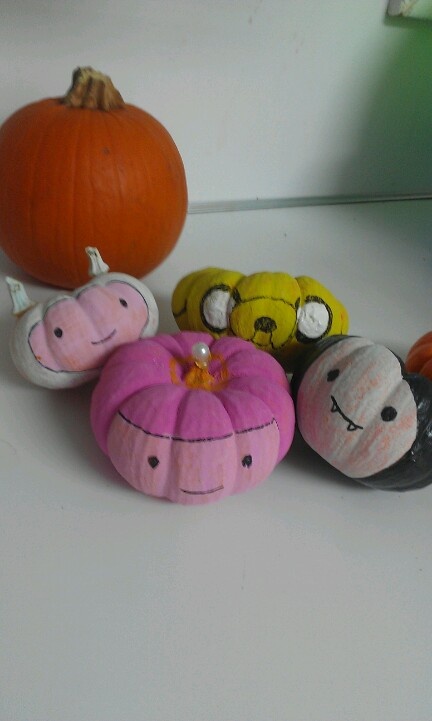 several painted pumpkins sitting next to each other on a white surface with a mirror in the background