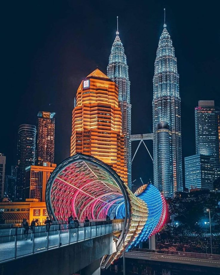 the city skyline is lit up at night with colorful lights and buildings in the background