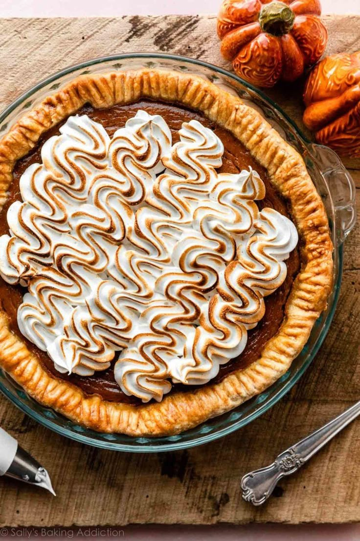 a pie with meringue and whipped cream on top sitting on a wooden table