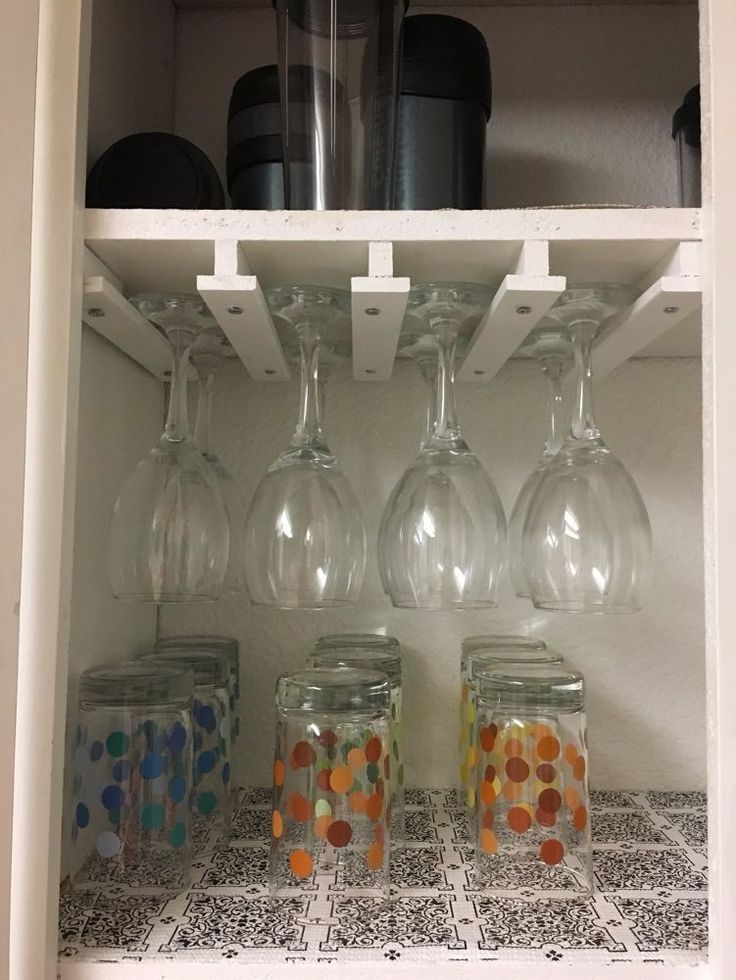 several wine glasses are sitting on the shelf in the kitchen, and one is filled with colorful confetti