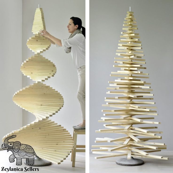 a woman standing next to a wooden christmas tree made out of strips of plywood