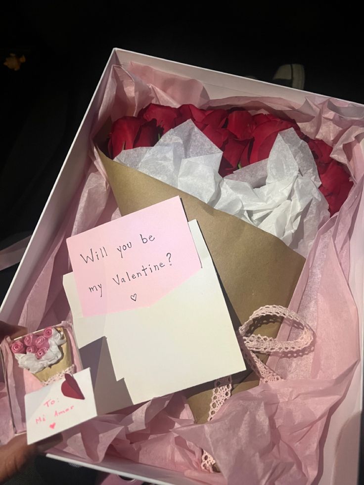 someone is holding a valentine's day card in a box with roses and paper