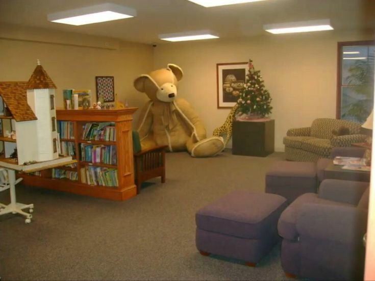 a large teddy bear sitting in the middle of a living room with furniture and bookshelves