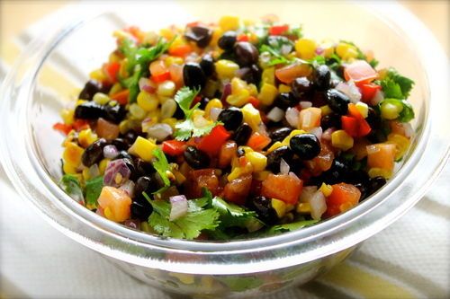 a glass bowl filled with corn and black beans