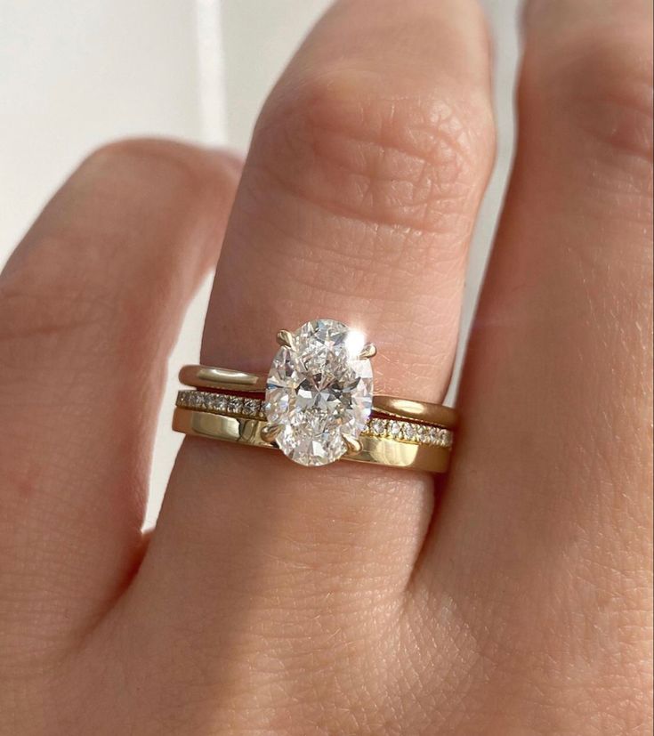 a woman's hand with a gold ring and a diamond engagement ring on it