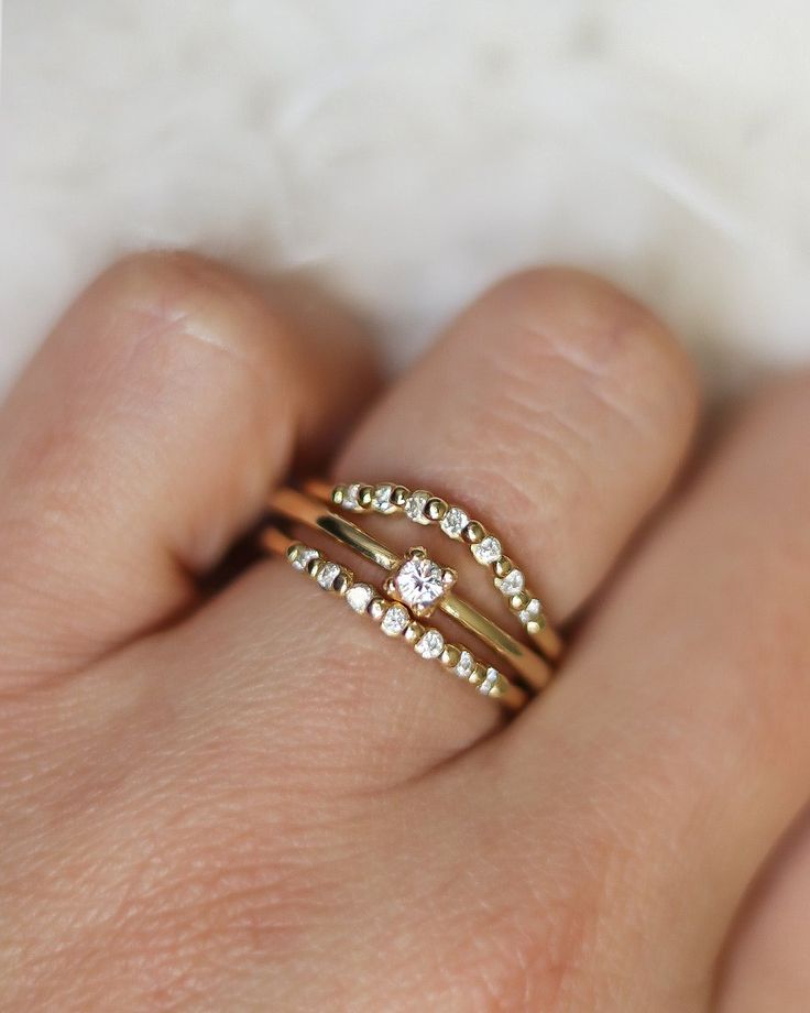 a woman's hand with two gold rings on top of her finger and the other ring