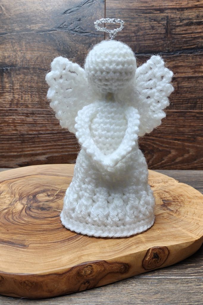 a white crocheted angel figurine sitting on top of a wooden board