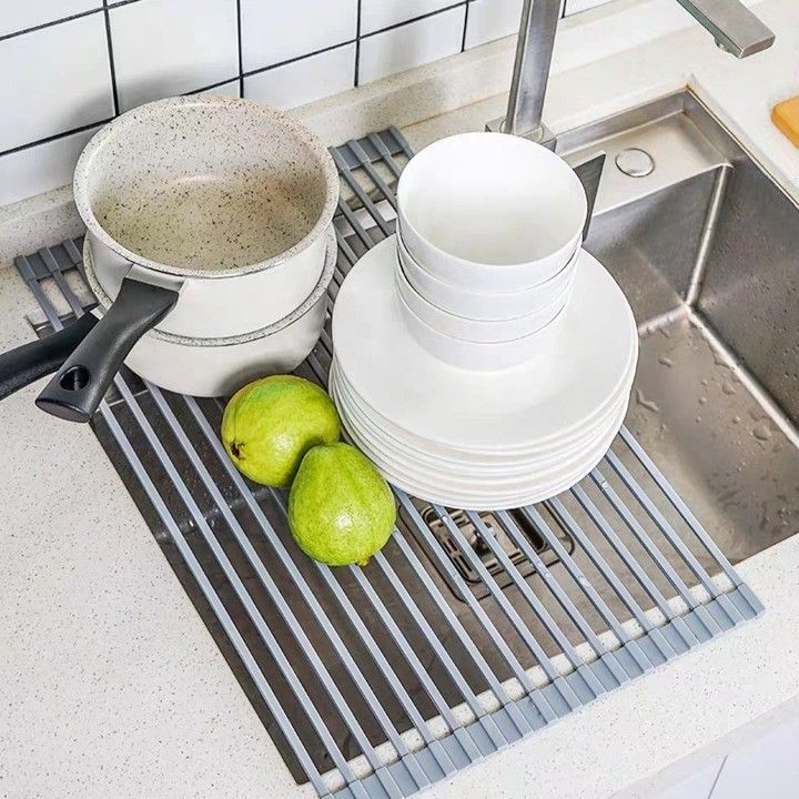 a kitchen sink filled with dishes next to a drainer and cutting board on the counter